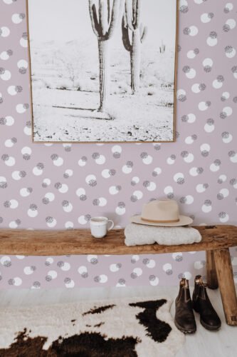Bold Dusty Rose Dots peel and stick wallpaper with scattered white circles and black speckled dots behind a wooden bench.