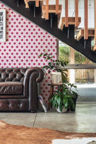 Retro Pink Polka Dot peel and stick wallpaper covers an accent wall beneath the staircase with bold pink dots on pale pink.