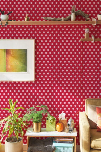 Red Retro Polka Dot peel and stick wallpaper with pink dots across a red wall behind floating shelves and decor.