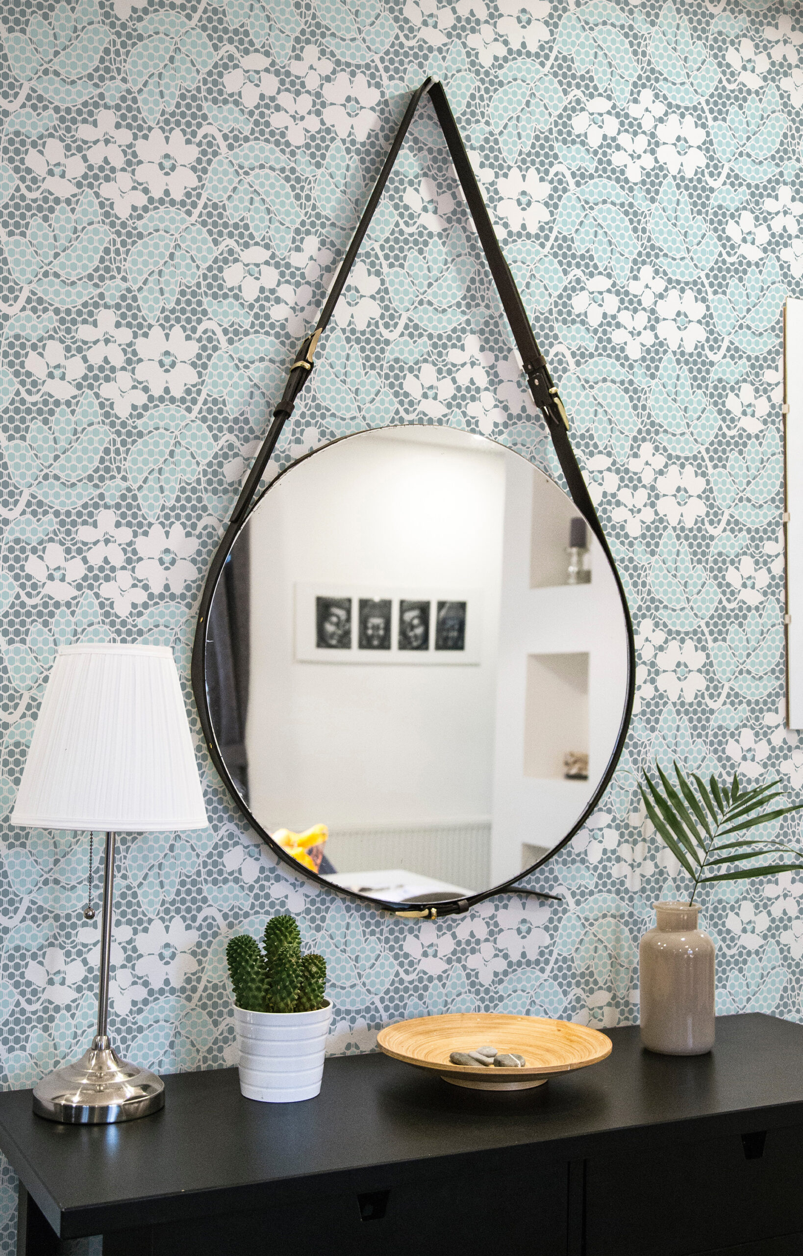 Fine Blue Lace Floral self-adhesive wallpaper with a light blue lace-like floral pattern behind a round hanging mirror.