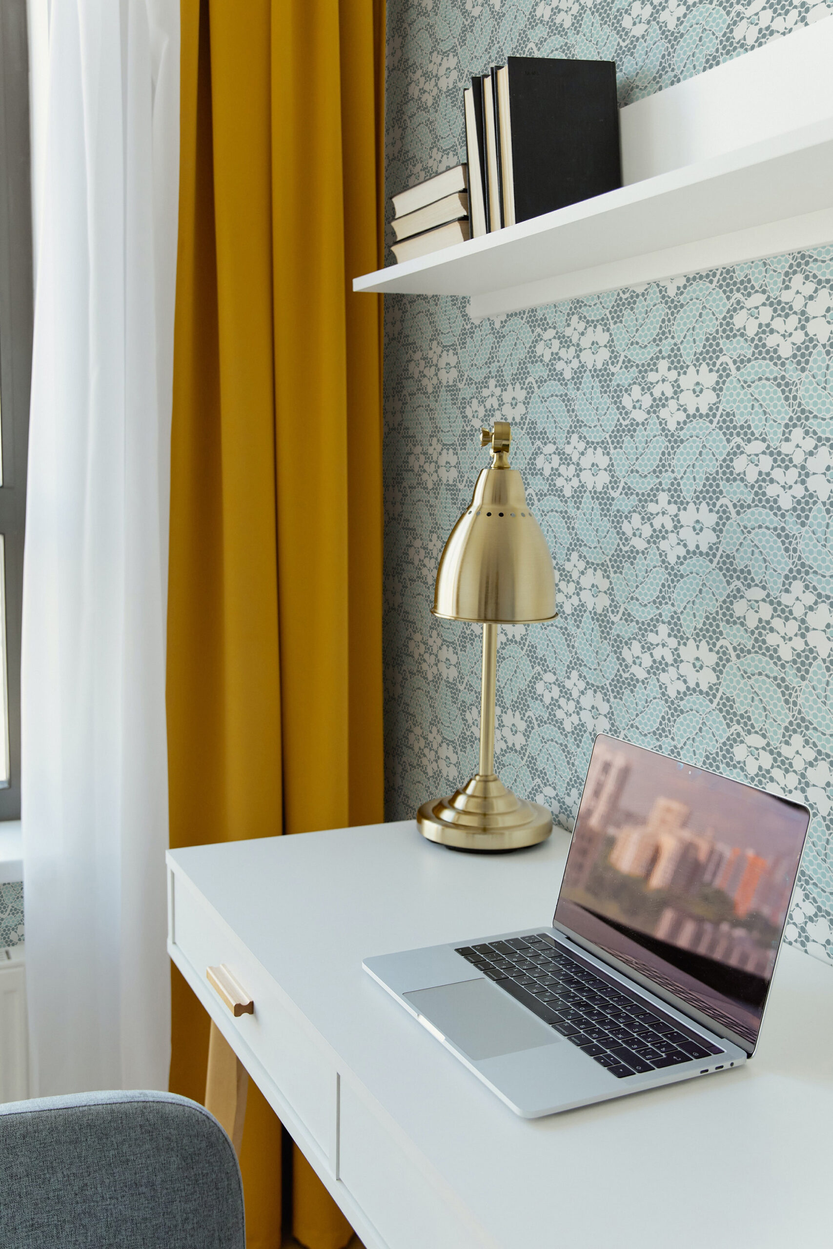 Fine Blue Lace Floral pre-pasted wallpaper with a delicate blue lace pattern behind a white desk and brass lamp.