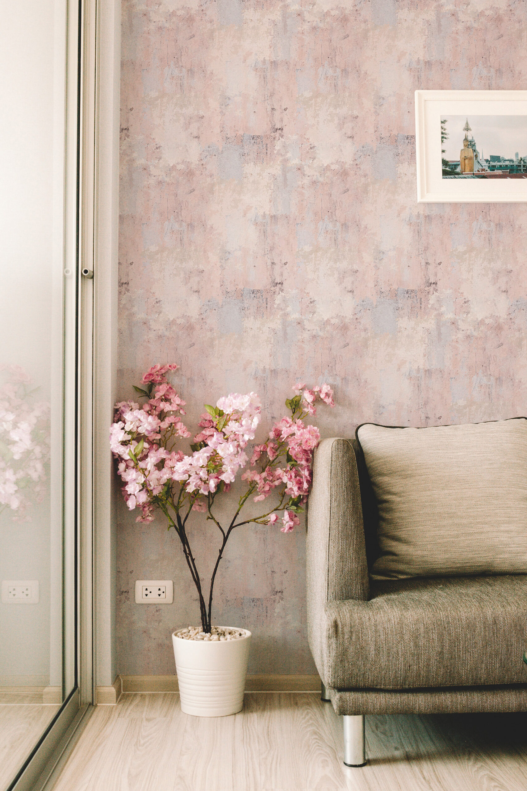 Soft Blush Wash Effect peel and stick wallpaper with a soft pink and gray wash effect shown as a full wall behind a sofa.