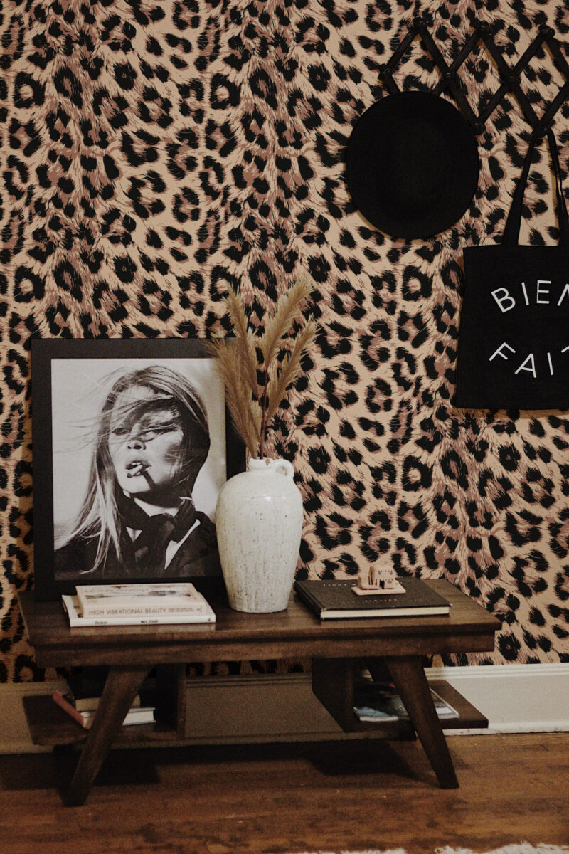 Bold Leopard Print Imitation peel and stick wallpaper in tan and black animal print, shown above a console table with decor.