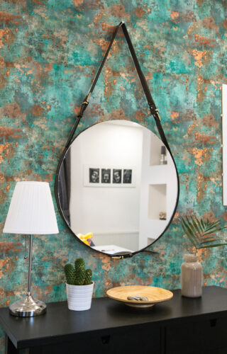 Turquoise Faux Texture peel and stick wallpaper on an accent wall behind a round hanging mirror and console table.