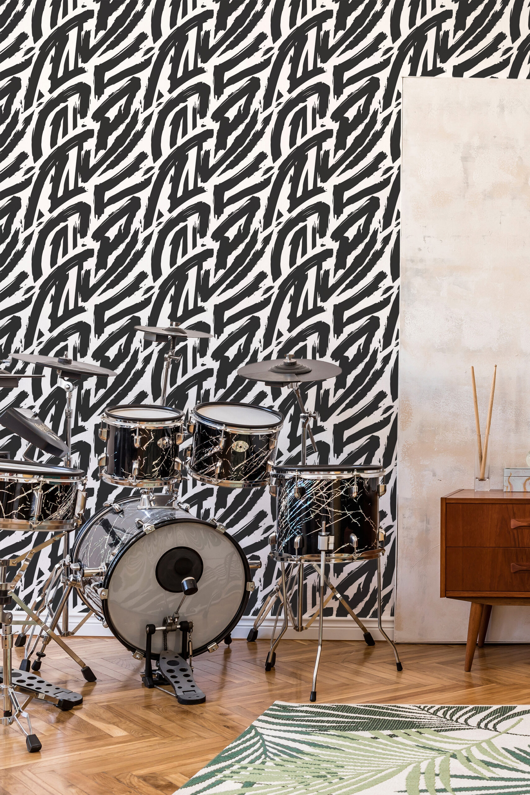 Bold Black Brush Strokes peel and stick wallpaper covers an accent wall behind a drum kit with sweeping black marks.