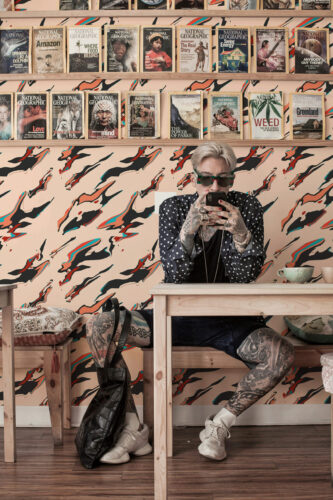 Liquid Ink Mirage peel and stick wallpaper with sweeping black and red streaks across the full wall behind shelving.