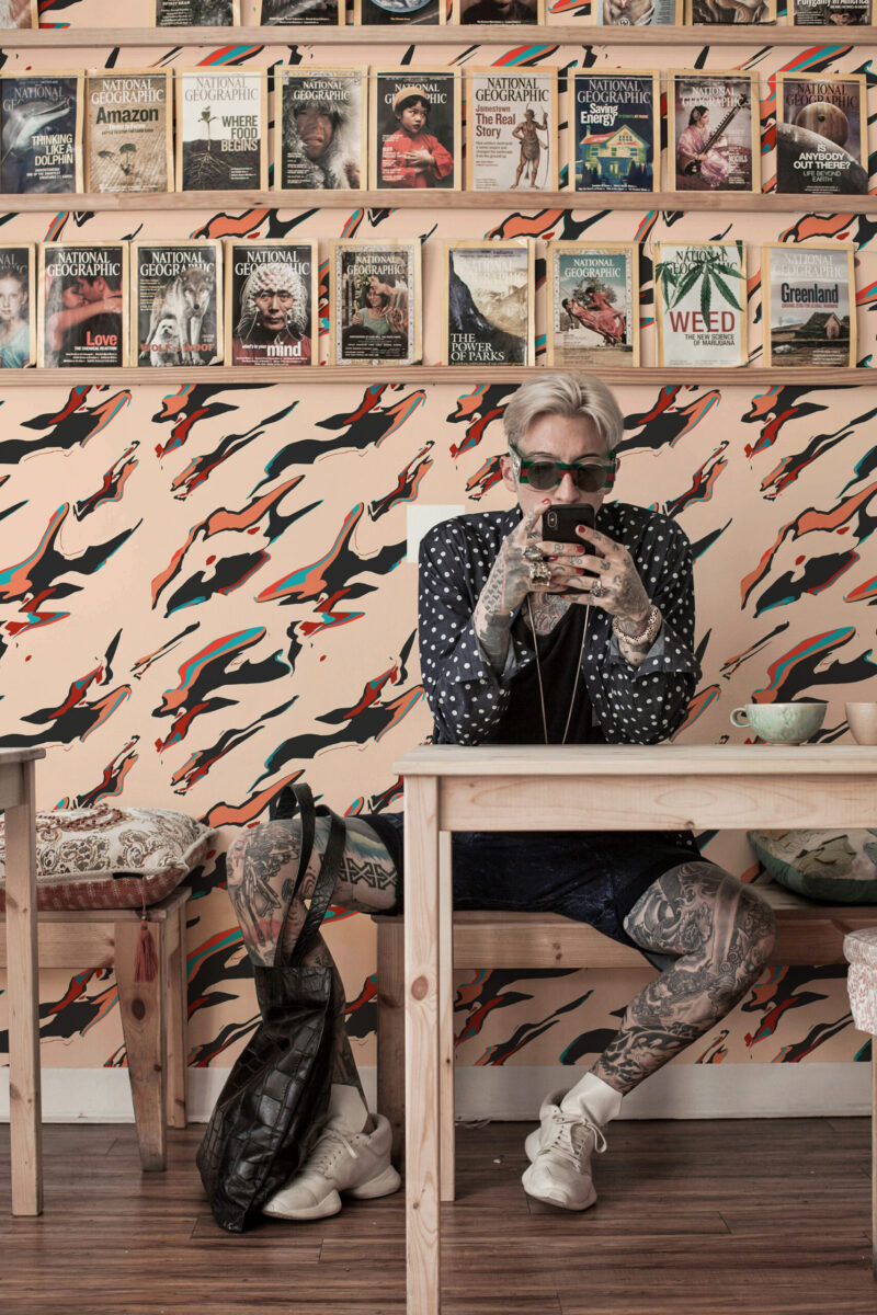 Liquid Ink Mirage peel and stick wallpaper with sweeping black and red streaks across the full wall behind shelving.