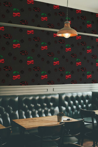 Skull Cherry Jackpot peel and stick wallpaper with red skull cherries and dice pattern on a dark wall above a booth seat.