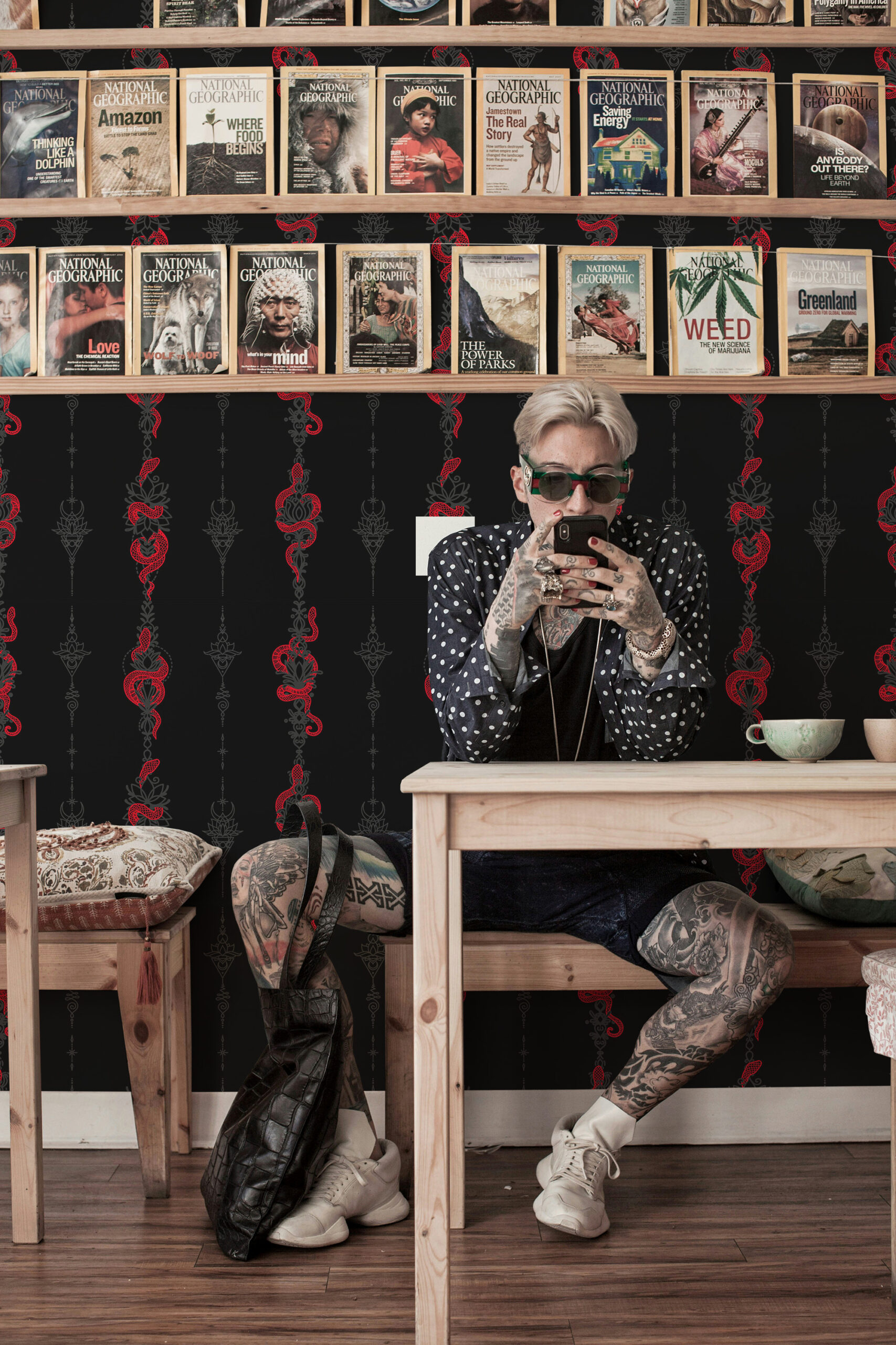 Serpent Alchemy shows vertical red snakes and ornate gray symbols on black traditional wallpaper behind a café seating nook.