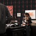 Serpent Alchemy peel and stick wallpaper with vertical red snake columns on a black background in a cafe setting.