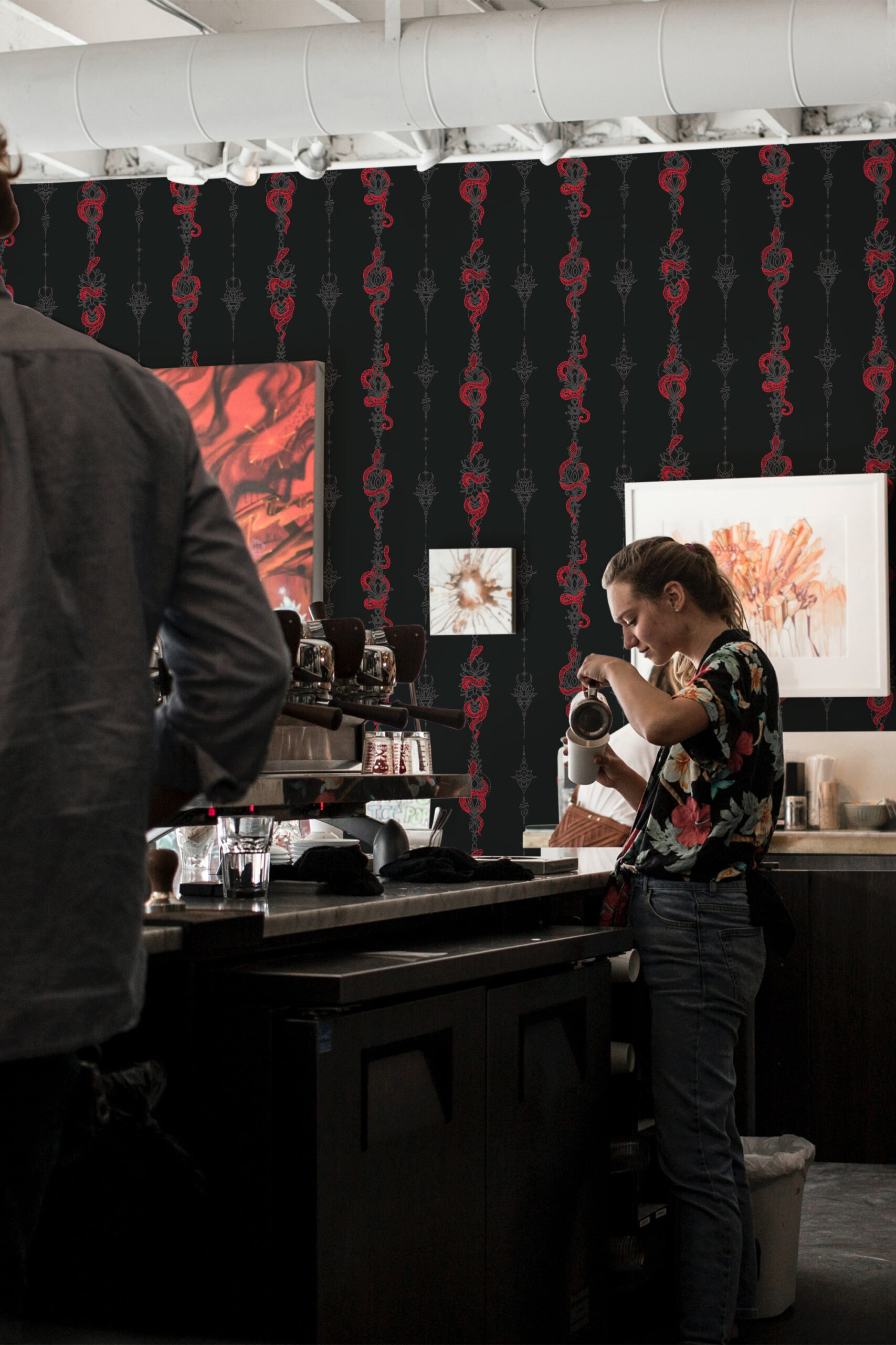 Serpent Alchemy peel and stick wallpaper with vertical red snake columns on a black background in a cafe setting.