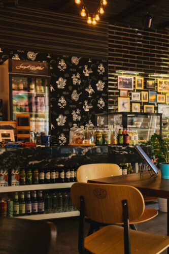 Retro Black Fiesta peel and stick wallpaper with tan fiesta illustrations and phrases creates an accent wall behind the bar counter.