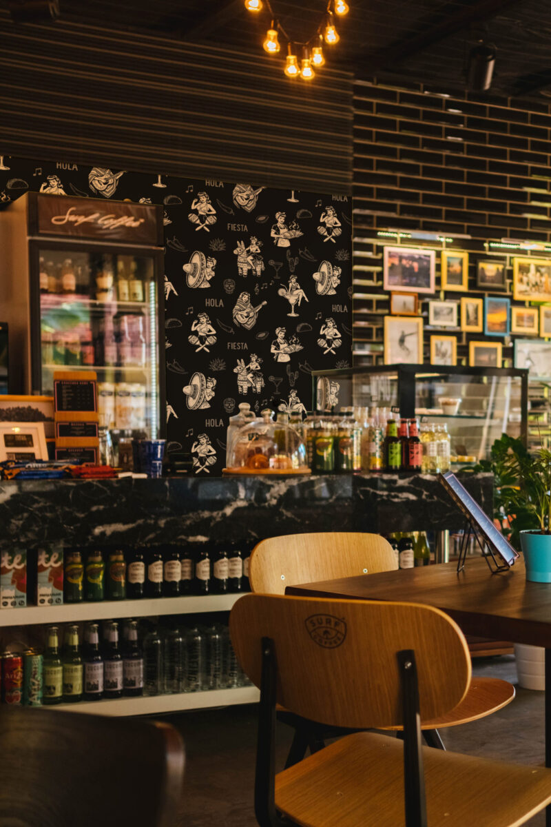 Retro Black Fiesta peel and stick wallpaper with tan fiesta illustrations and phrases creates an accent wall behind the bar counter.