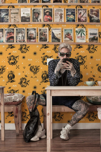 Retro Tattoo Beauties peel and stick wallpaper with black retro pinup figures and icons scattered over a mustard backdrop.