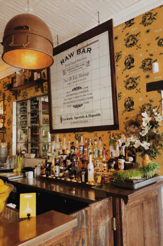 Retro Tattoo Beauties pre-pasted wallpaper with black pinup illustrations covering a bar wall behind a hanging menu board.