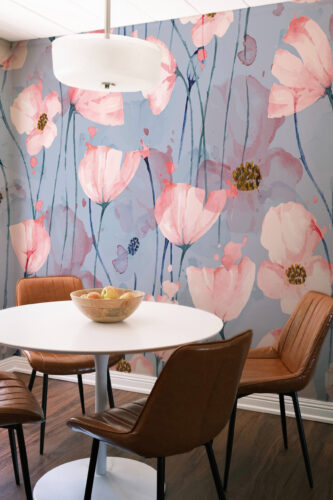 Airy Pink Poppy Blossoms removable wall mural covering a dining nook wall with watercolor pink poppies on a soft blue background.