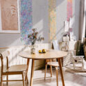 Floral Paintbrush Cascade wall mural shown as tall floral paint stripes on a gray dining room wall above a round table.