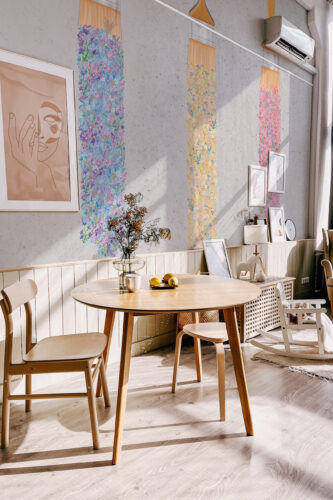 Floral Paintbrush Cascade wall mural shown as tall floral paint stripes on a gray dining room wall above a round table.