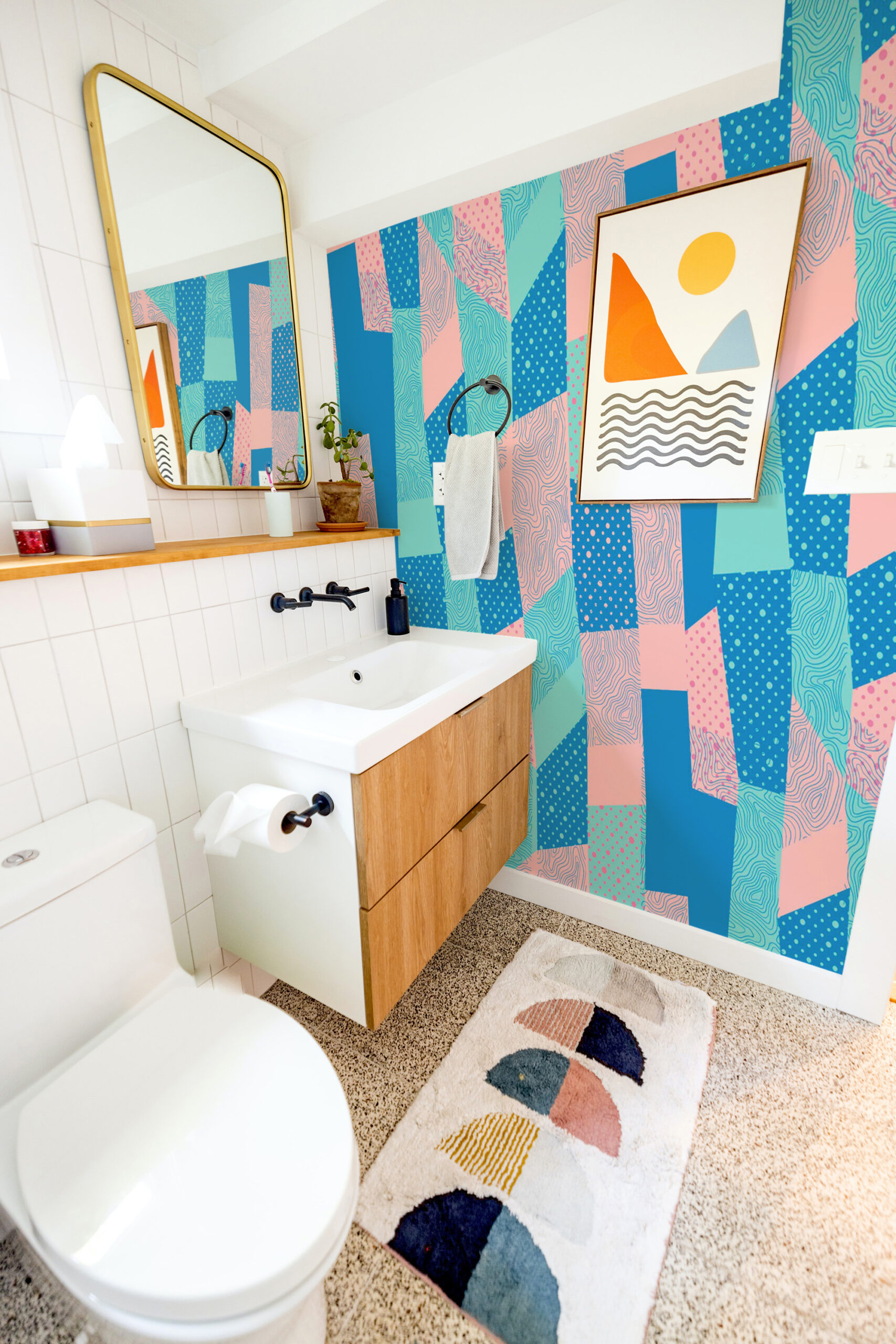 Retro Blue Geometric Patchwork covers a bathroom accent wall as a wall mural with bold teal, blue, and pink abstract blocks.