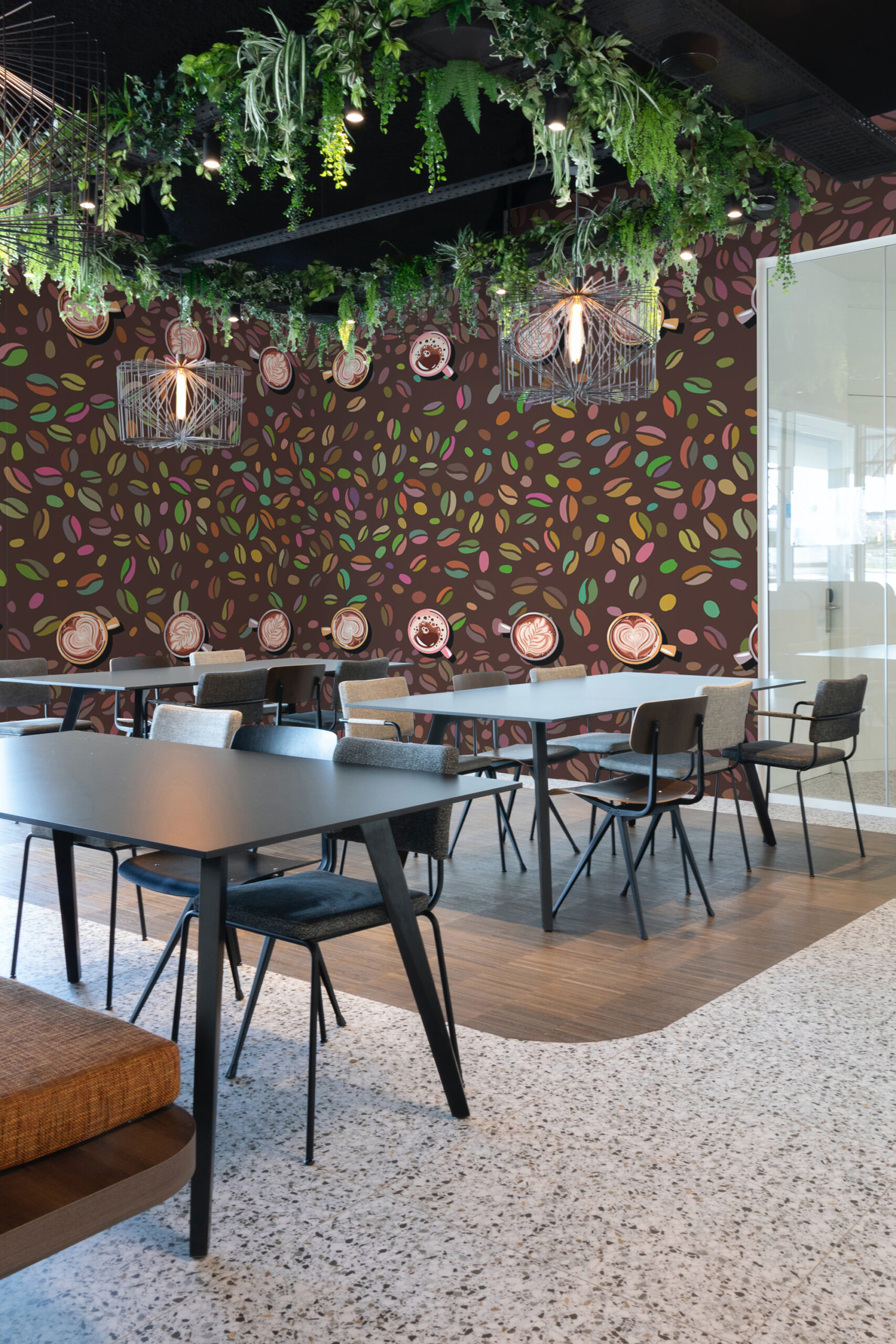 Cozy Coffee Beans peel and stick wallpaper mural covers a cafe seating wall with colorful coffee beans and latte art cups on a dark background.