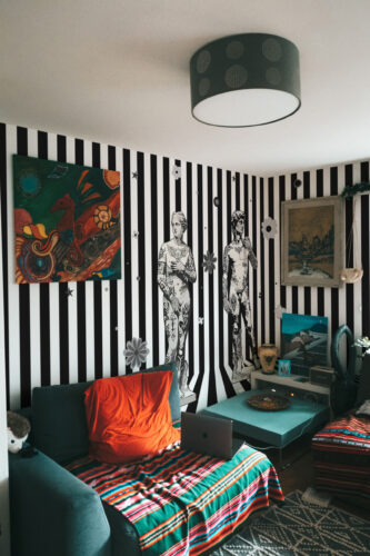 Inked Renaissance Statues black-and-white striped wallpaper mural wraps the bedroom corner with two tattooed classical statues.