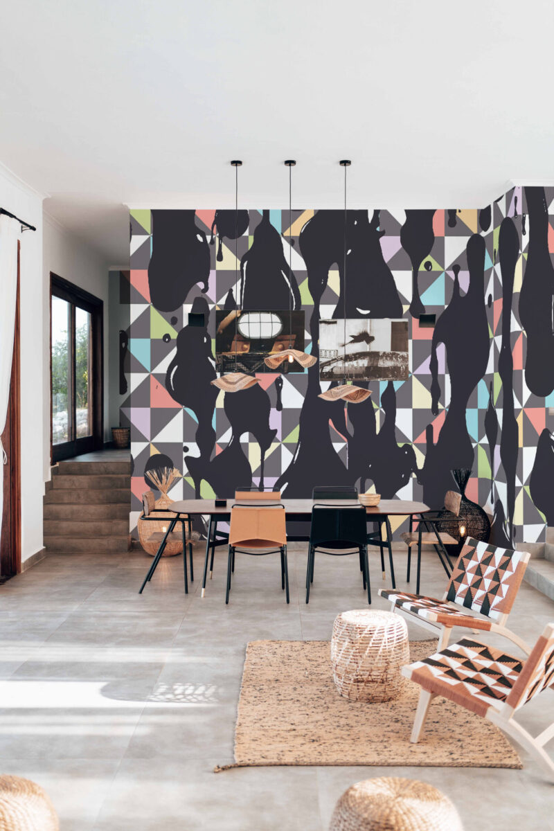 Ink Drips Geometric shows bold black drips over pastel triangles on a full-wall peel and stick wallpaper mural behind a dining table.