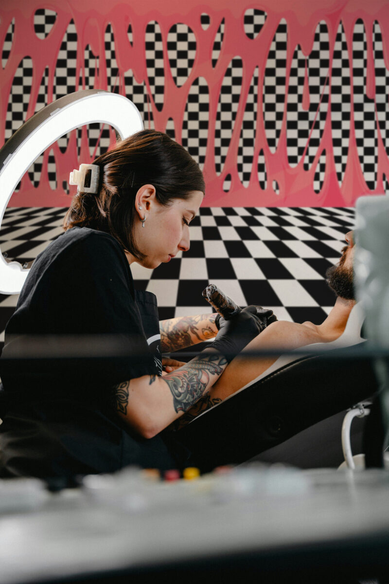 Bubblegum Drip Checkerboard Effect peel and stick wall mural filling the studio wall with pink dripping shapes over a black-and-white grid.