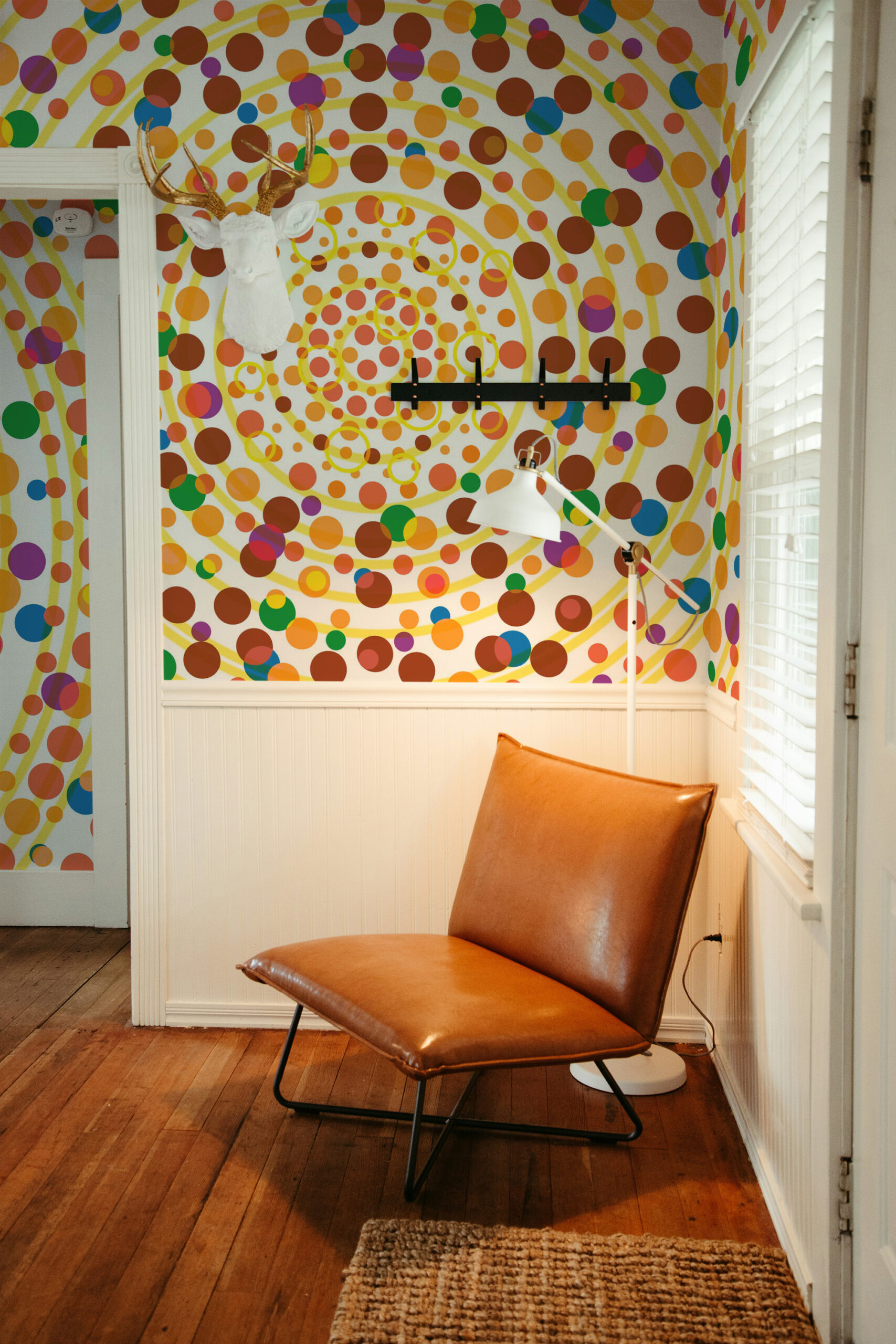 Yellow Dot Vortex removable wallpaper mural wraps an accent wall with swirling yellow rings and multicolored dots in a corner nook.