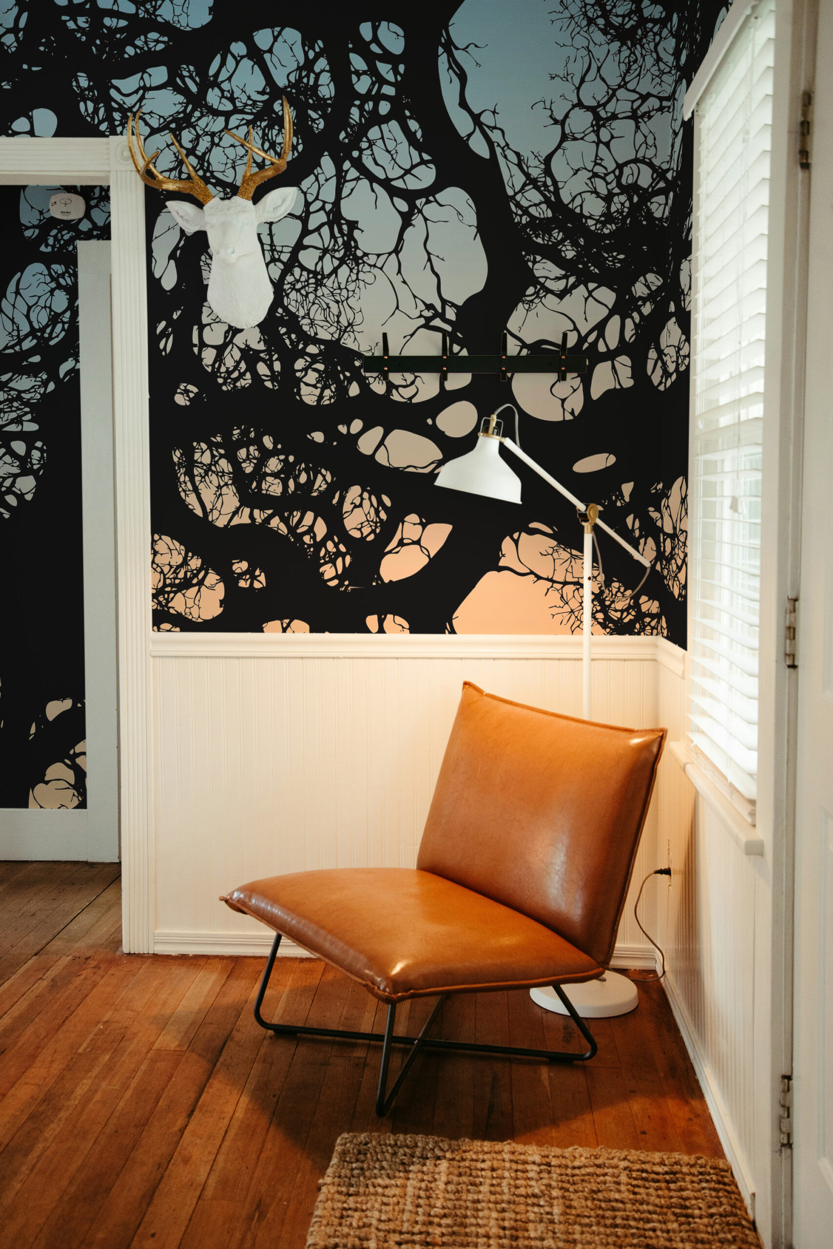 Moody Branch Canopy removable wallpaper mural with bold black tree branches across a full corner wall above white wainscoting.