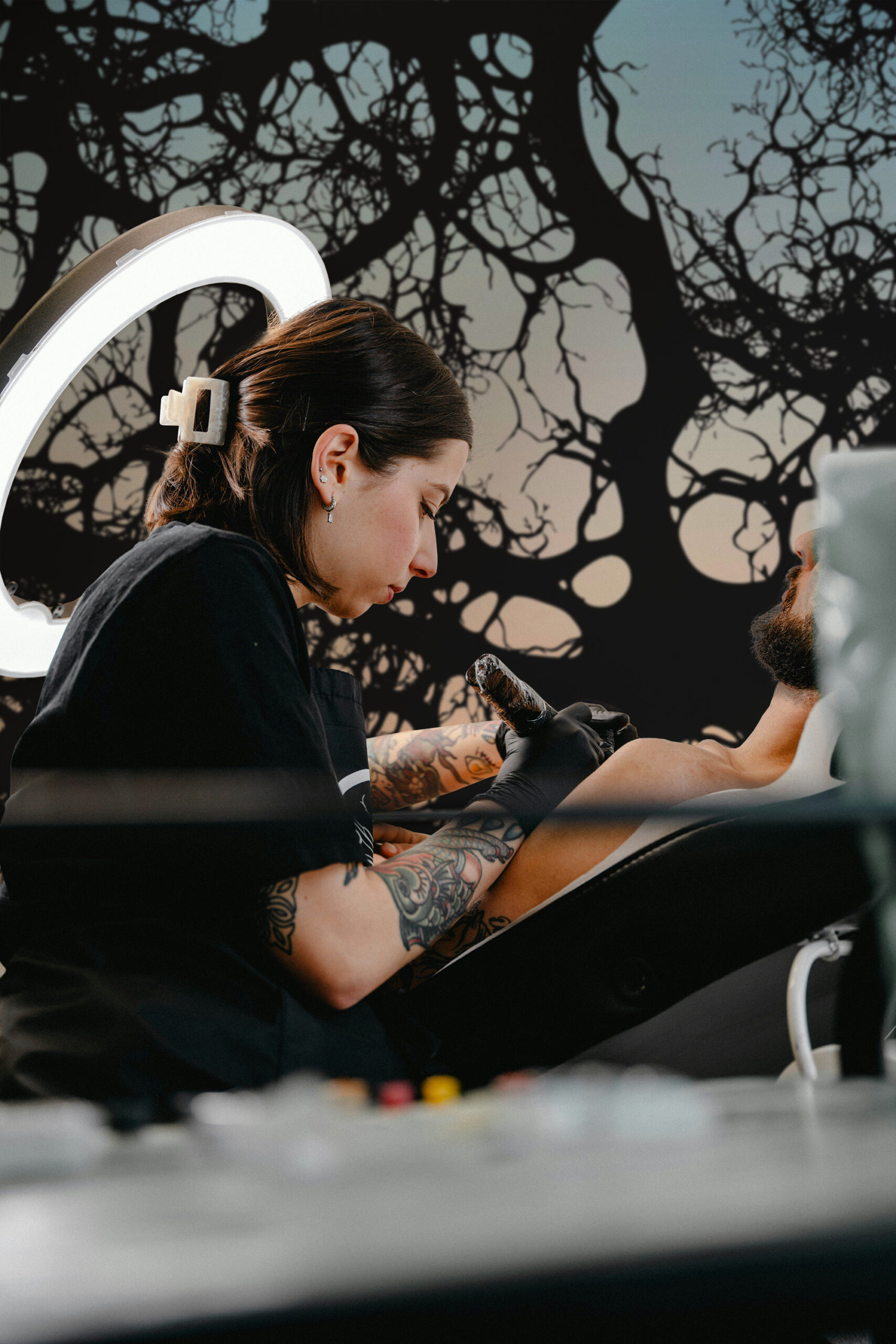 Moody Branch Canopy wall mural covers the studio wall with dark, tangled tree branches against a muted sky backdrop.