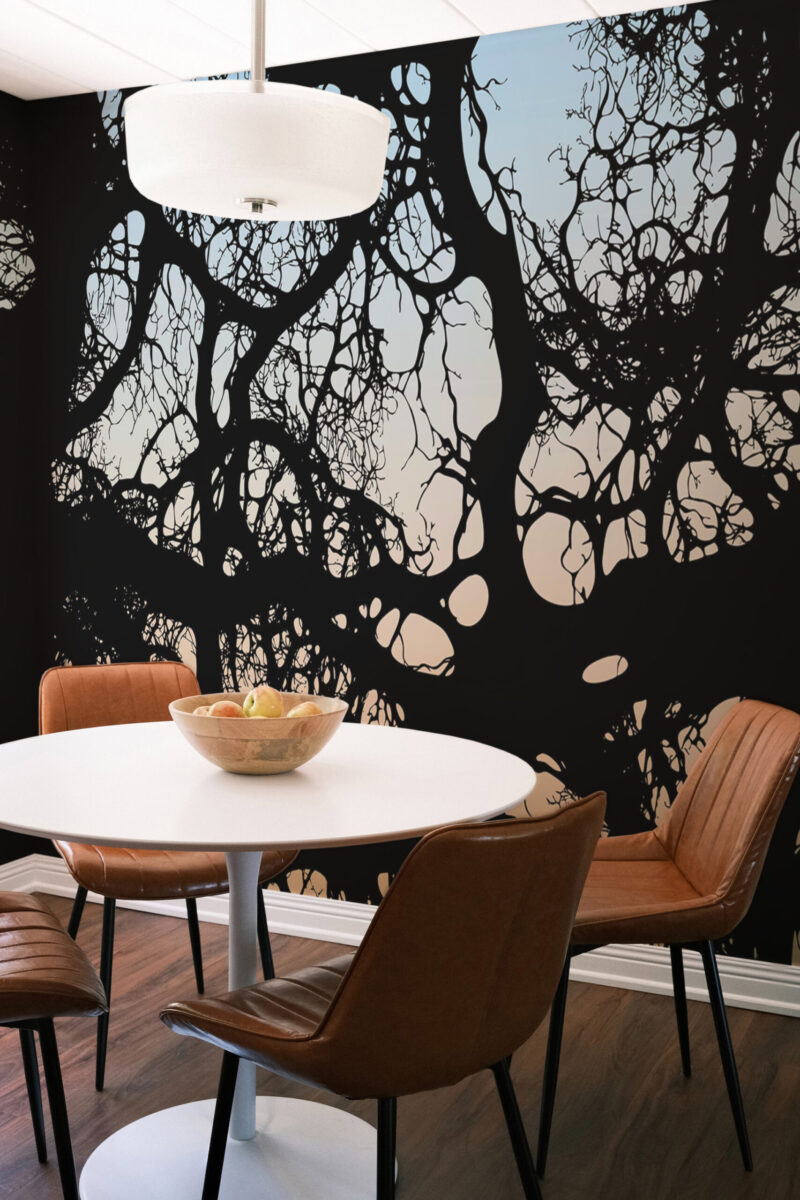 Moody Branch Canopy wall mural spans the dining room accent wall with bold black branches over a pale sky gradient.