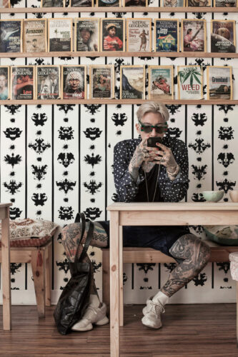 Rorschach Ink Stripes peel and stick wallpaper with black inkblot stripes on white, shown as a full wall behind shelves.