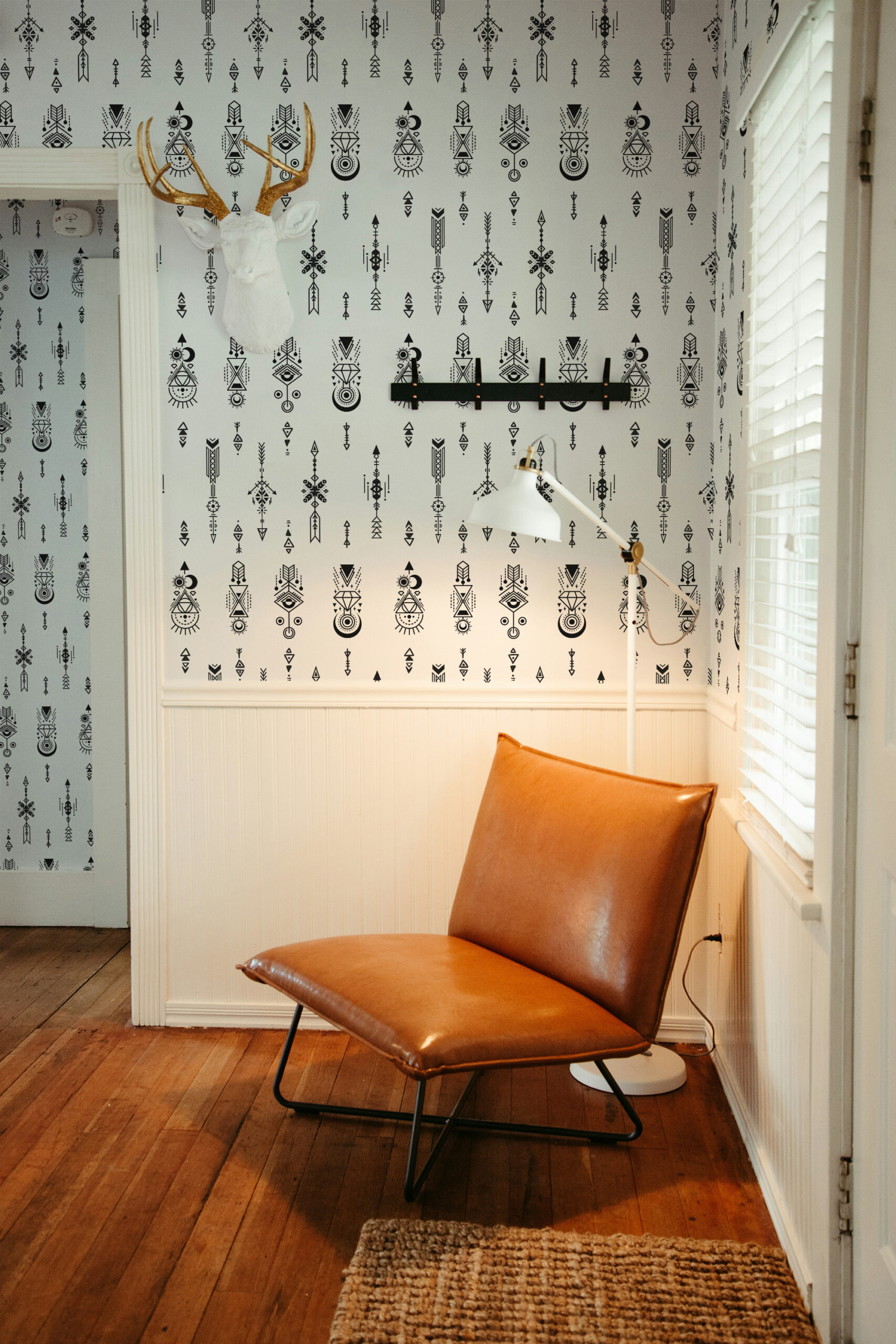 Sacred Tattoo Sigils self-adhesive wallpaper with black geometric symbols on white, covering a small corner wall by a window.