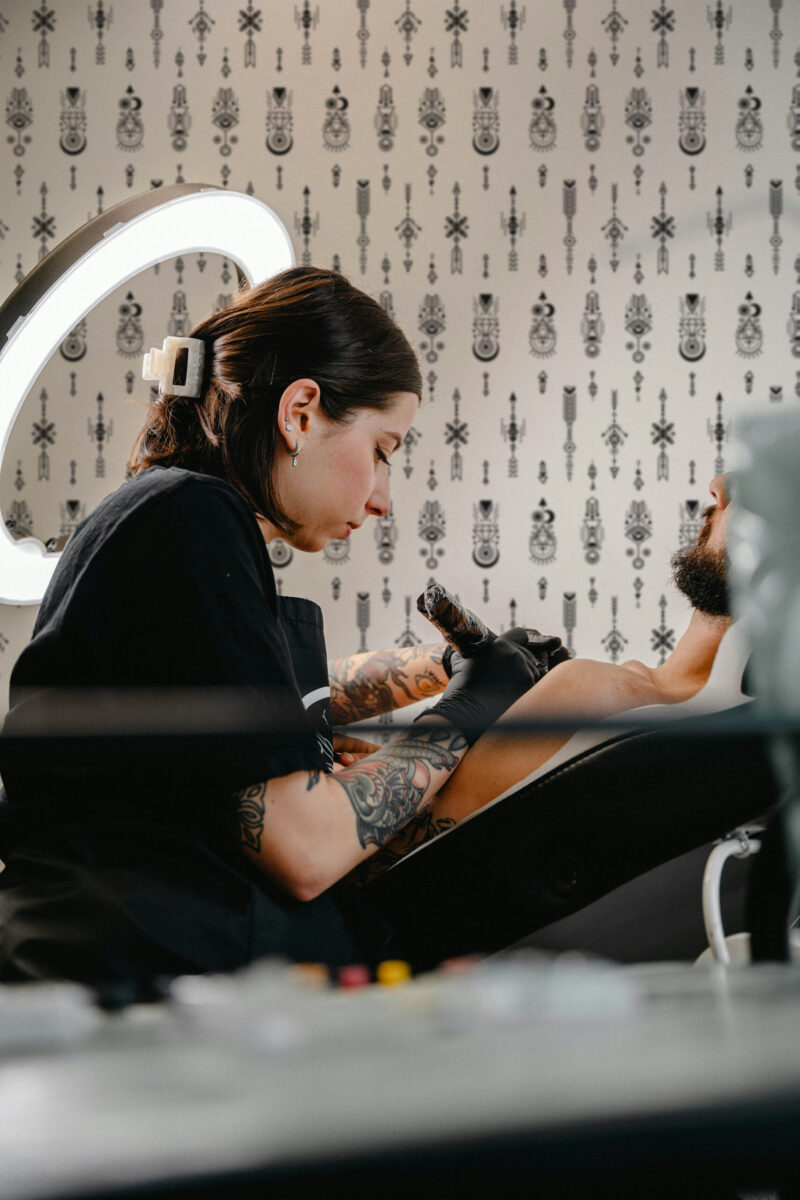 Sacred Tattoo Sigils peel and stick wallpaper with black tattoo-inspired symbols and arrows across a light background.