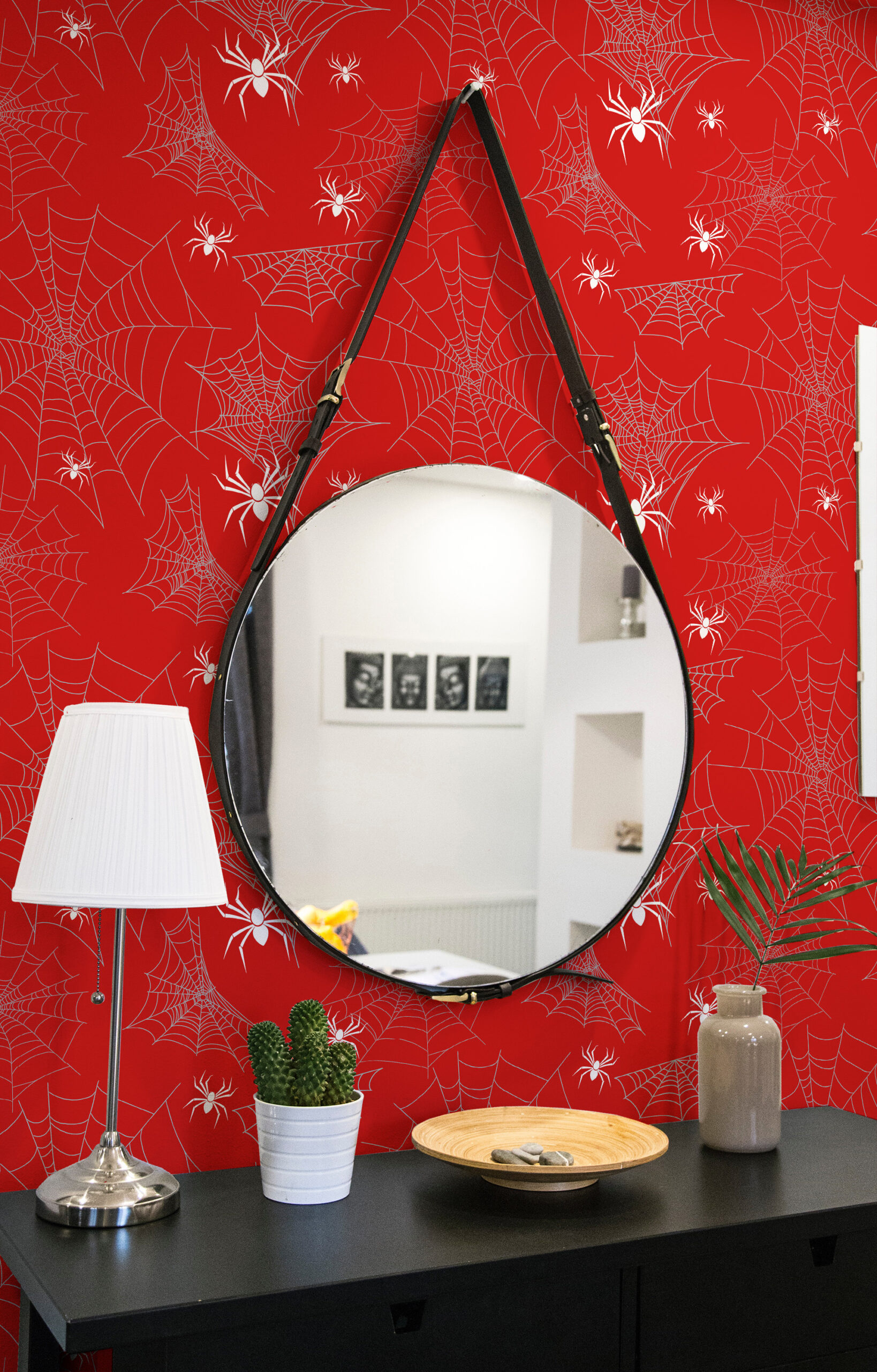 Bold Red Spider non-pasted wallpaper with white webs and spiders, shown behind a round hanging mirror above a dresser.
