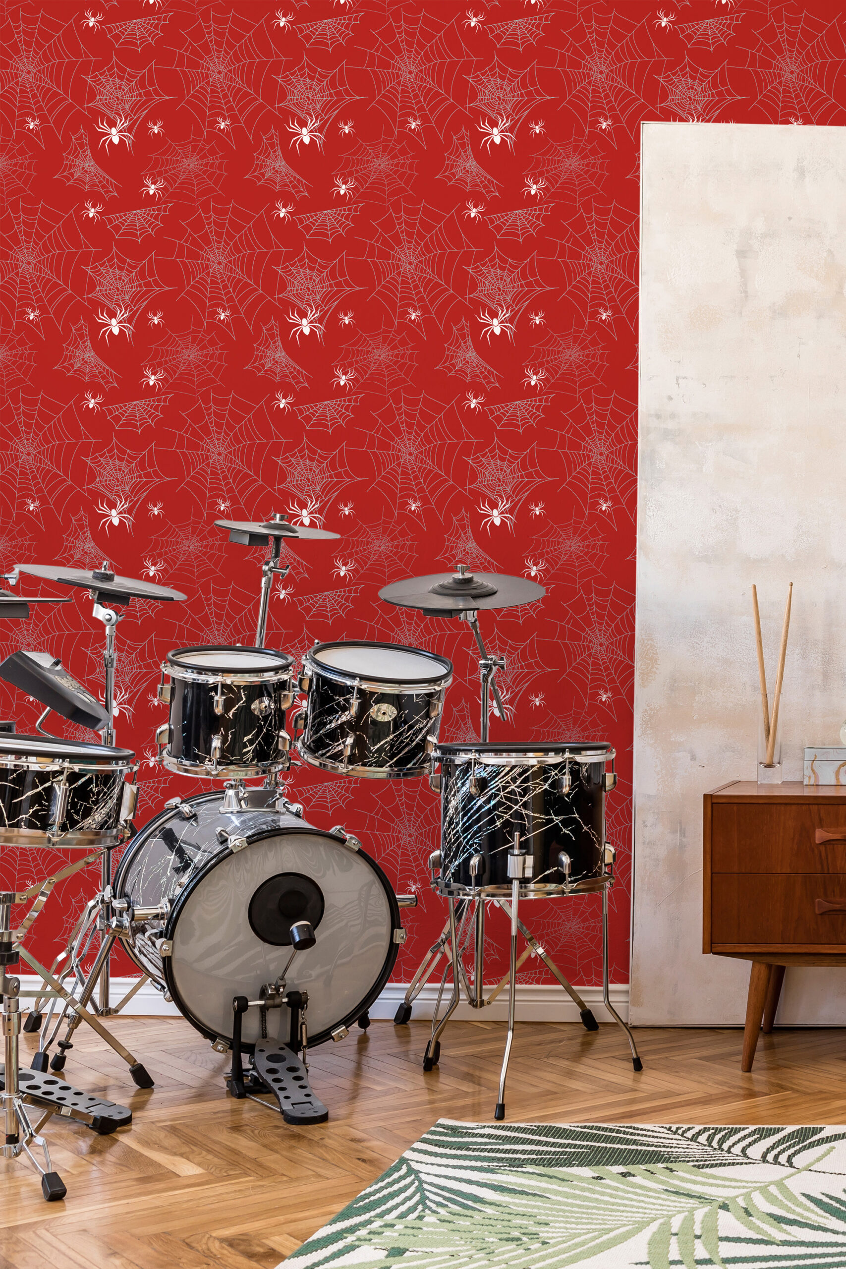 Bold Red Spider self-adhesive wallpaper with white web and spider pattern across an accent wall behind a drum set.