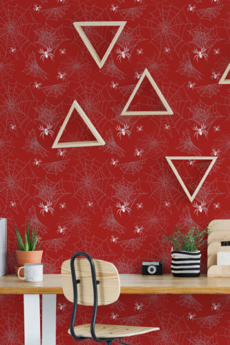Bold Red Spider peel and stick wallpaper with white webs and spiders across a full wall behind a desk.