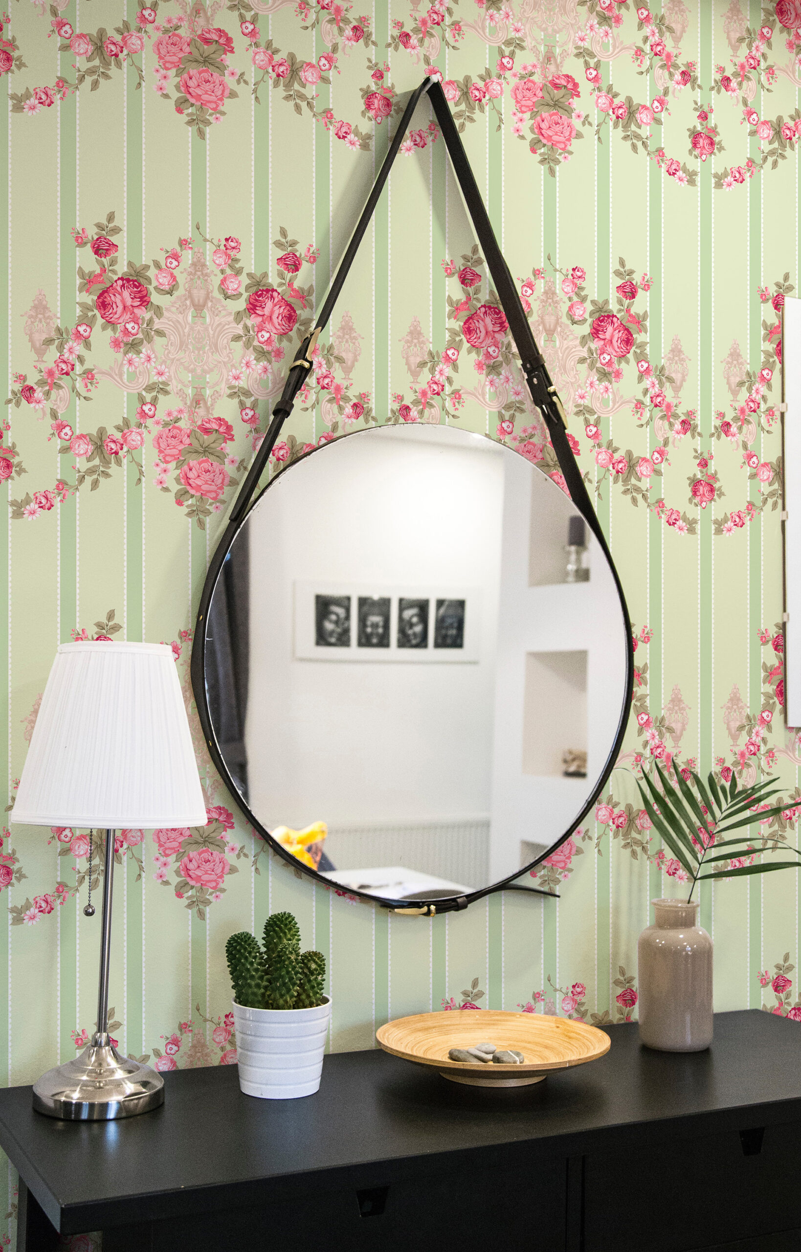 Vintage Floral Stripe pre-pasted wallpaper with vertical sage stripes and pink rose garlands behind a round wall mirror.