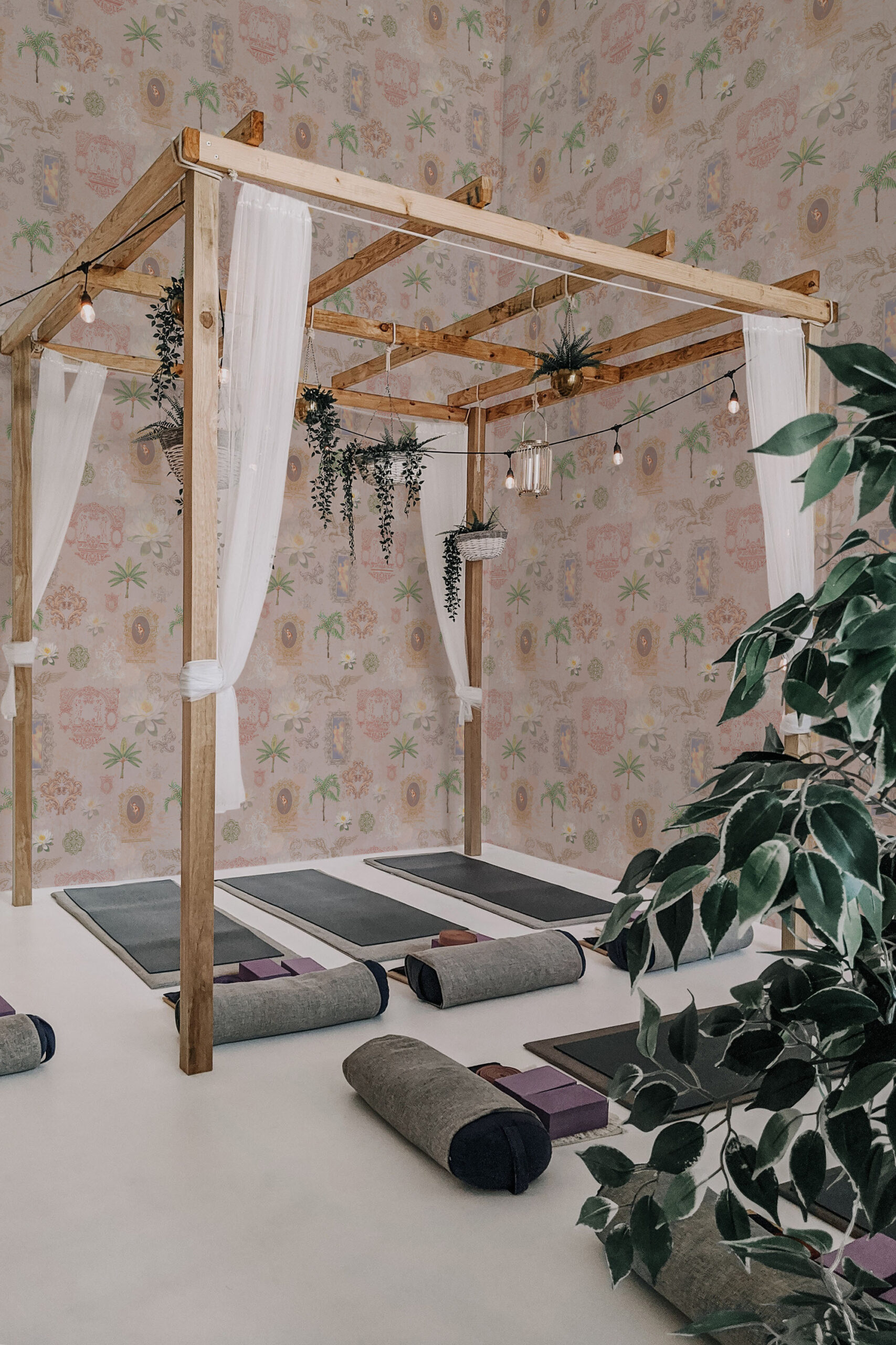 Whimsical Beige Lotus pre-pasted wallpaper with lotus flowers, palms, and framed portraits covering the studio walls.
