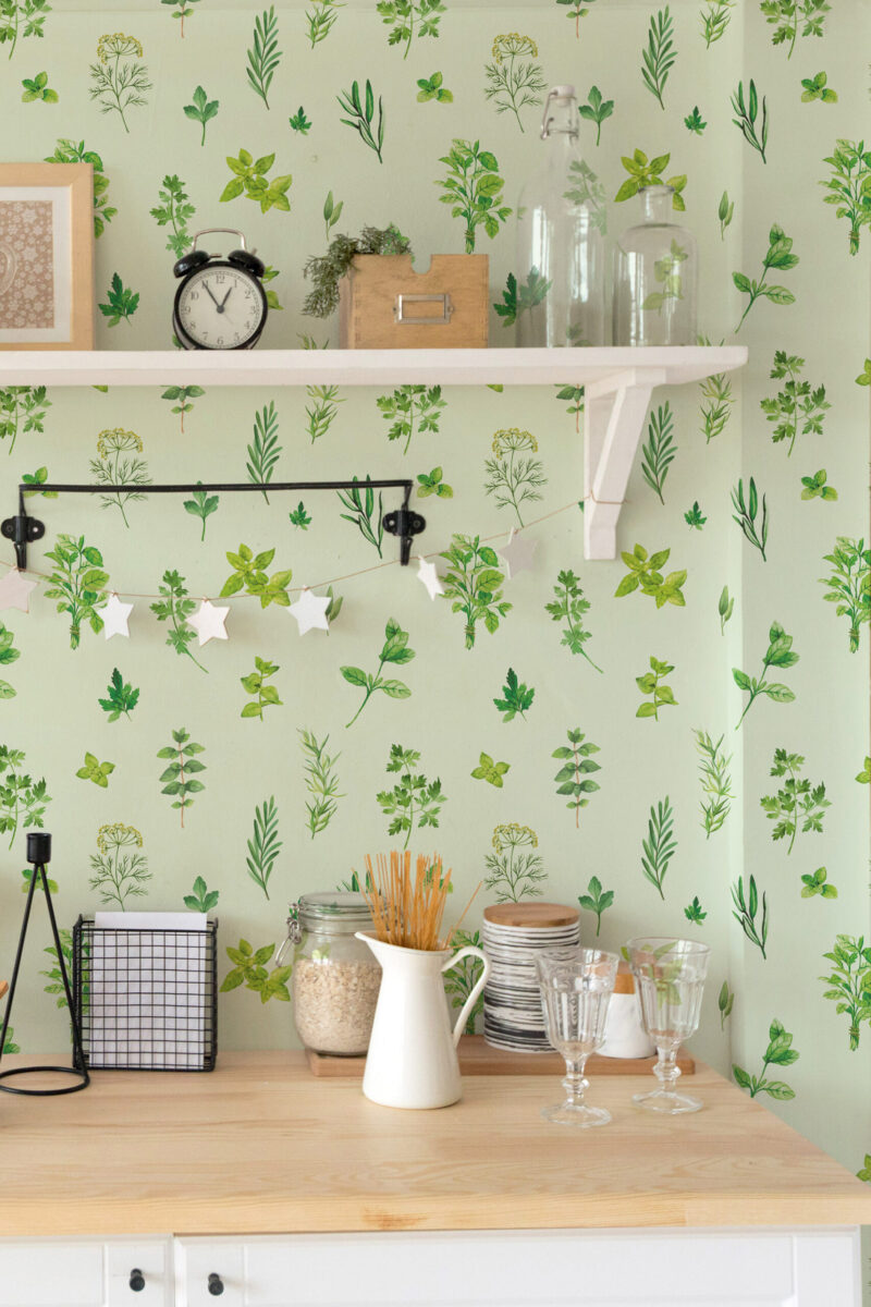 Delicate Green Herb peel and stick wallpaper with scattered illustrated green herbs on a pale mint wall behind open shelves.