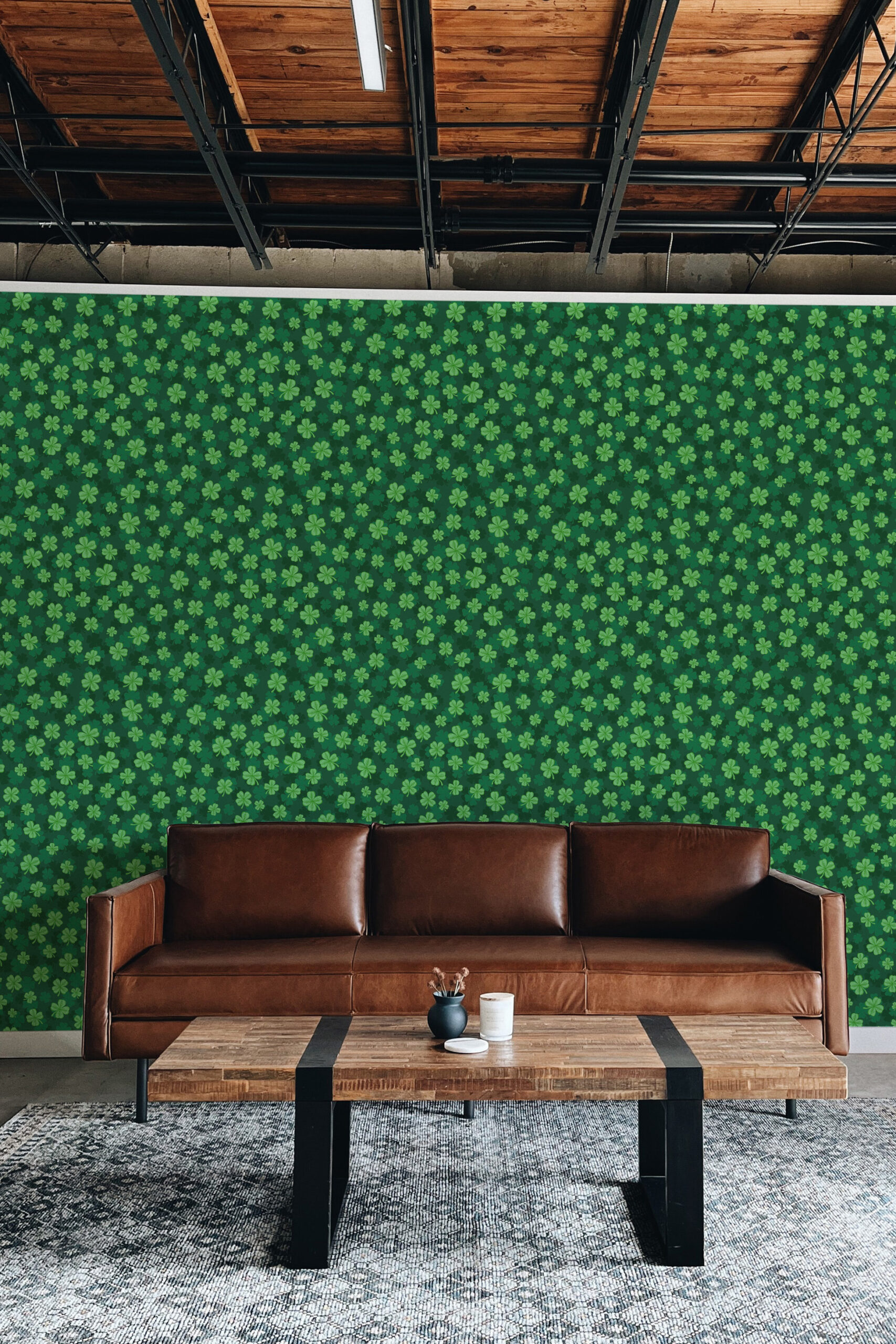 Four Leaf Clover self-adhesive wallpaper with a small clover pattern covering a full accent wall behind a brown leather sofa.