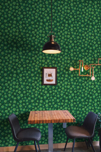 Four Leaf Clover peel and stick wallpaper covers the wall in a lively clover pattern behind a small table and chairs.