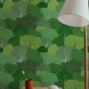 Whimsical Tree peel and stick wallpaper with layered leafy canopies in varied green tones behind a small vanity table.