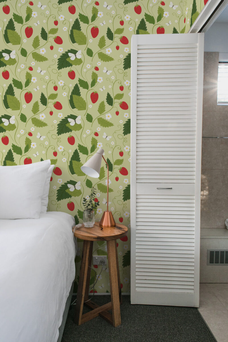 Bedroom featuring strawberry wallpaper with bedside table and lamp