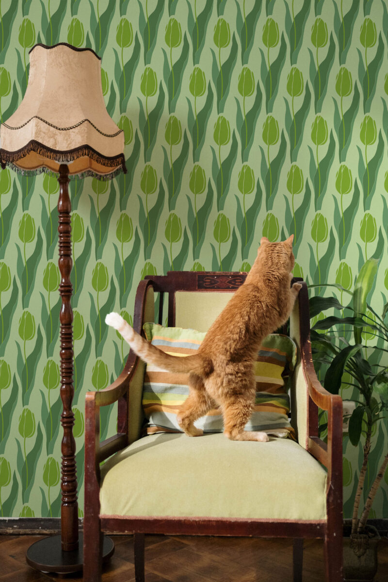 Seamless Green Tulip peel and stick wallpaper with repeating tulip buds and wavy leaves in layered green tones behind a chair.