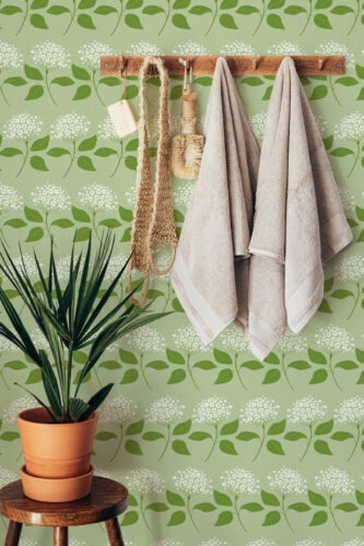 Delicate Green Floral peel and stick wallpaper with leafy vines and small white blooms across the wall behind hanging towels.