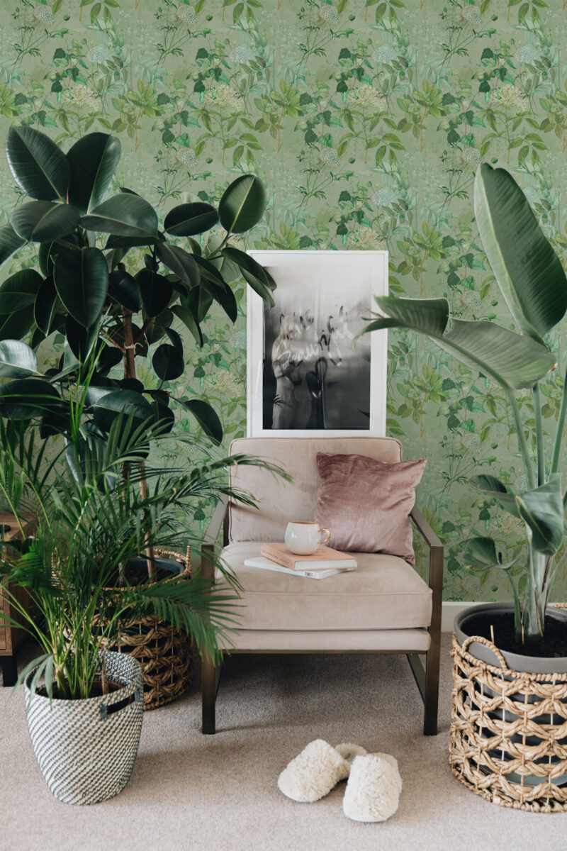 Dreamy Sage Botanical peel and stick wallpaper with soft green vines and tiny blossoms behind a cozy armchair.