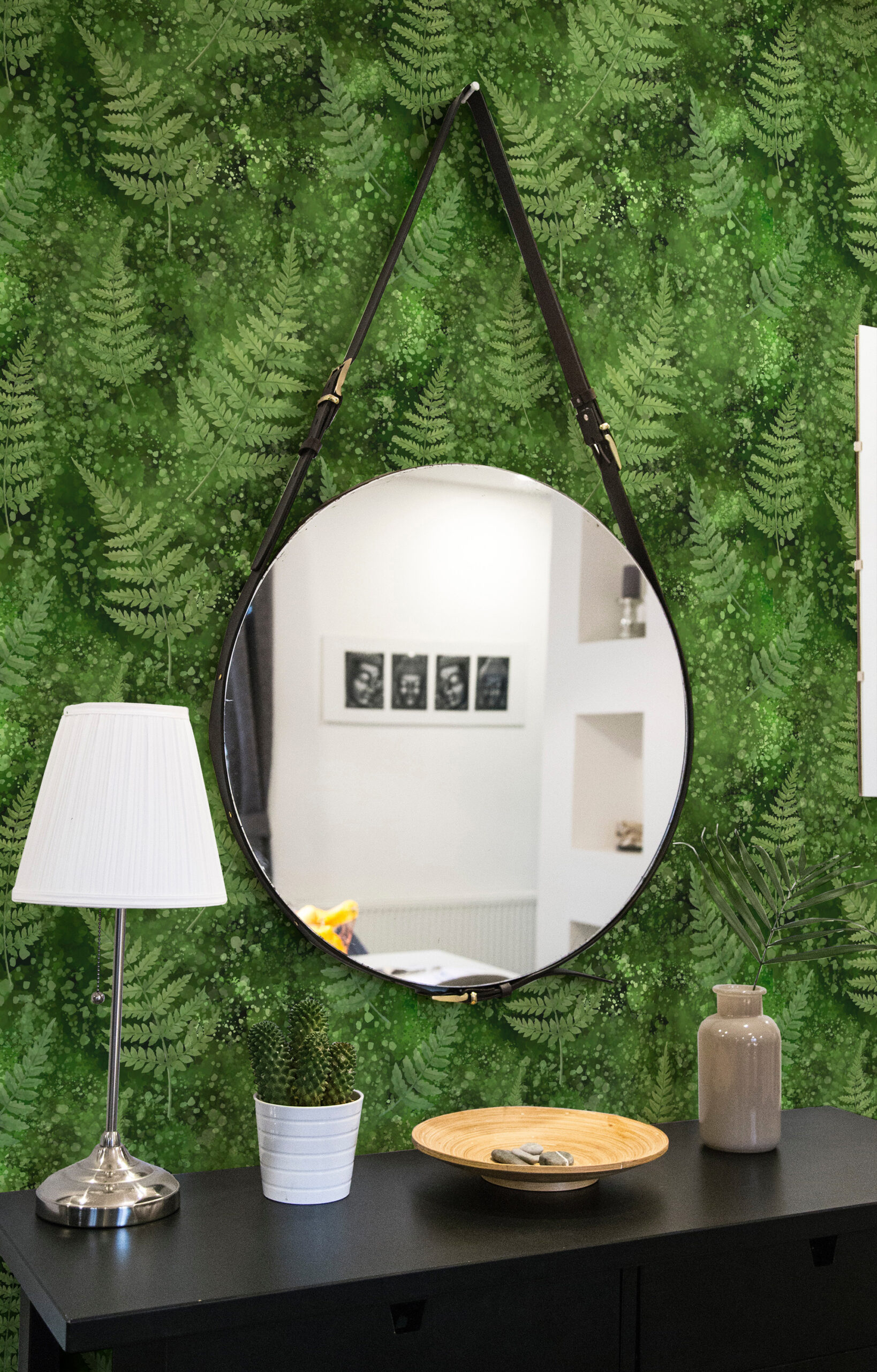 Green Moss and Fern peel and stick wallpaper with layered fern fronds and speckled green wash behind a round hanging mirror.