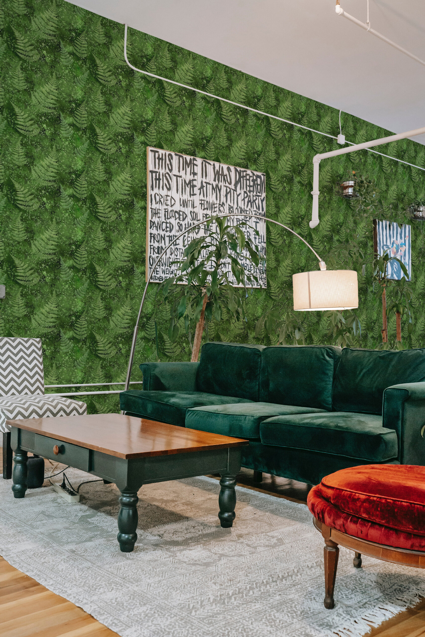 Green Moss and Fern self-adhesive wallpaper with layered fern fronds covering the wall behind a green sofa.