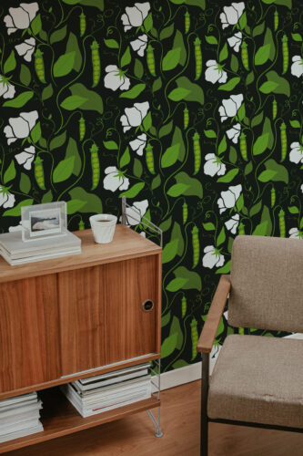 Bold Pea Pod peel and stick wallpaper with green vines, pea pods, and white flowers behind a chair.